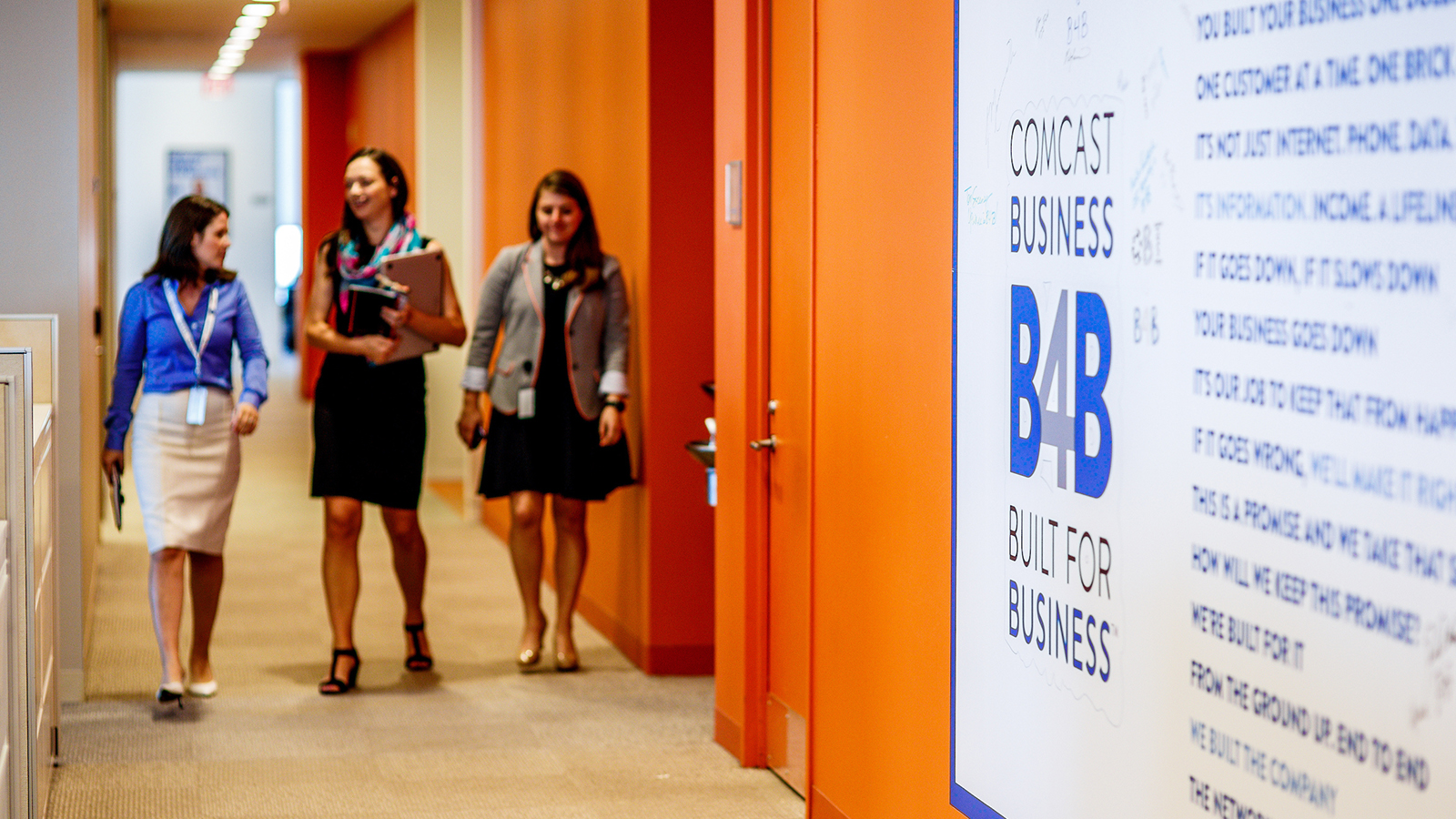 Three coworkers walk down a hallway together.